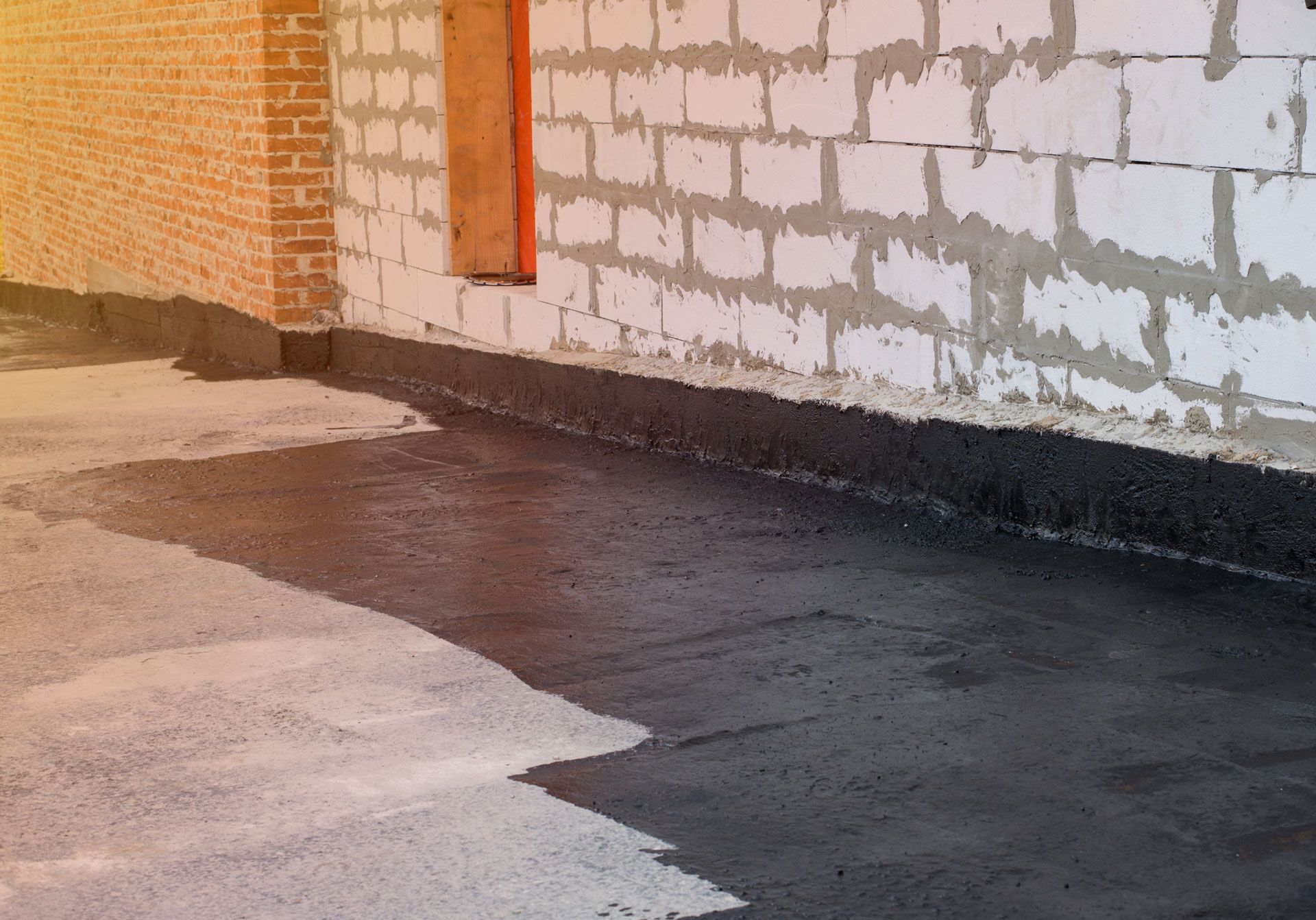 Newly poured concrete floor meets a plastered wall.
