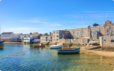 Boats in a harbor with buildings on the shoreline under a clear blue sky.