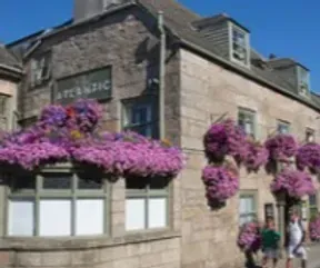 Stone building with "ATLANTIC" sign, purple flower baskets, two people in front.
