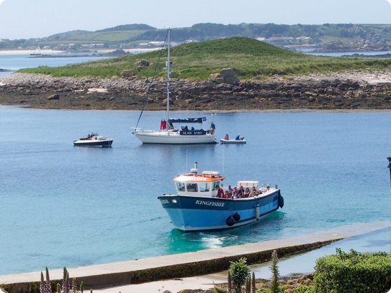 Boats in turquoise water near a small island on a sunny day.