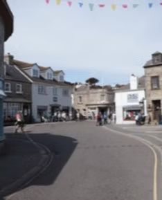 Street scene with buildings, pedestrians, and colorful bunting under a bright sky.