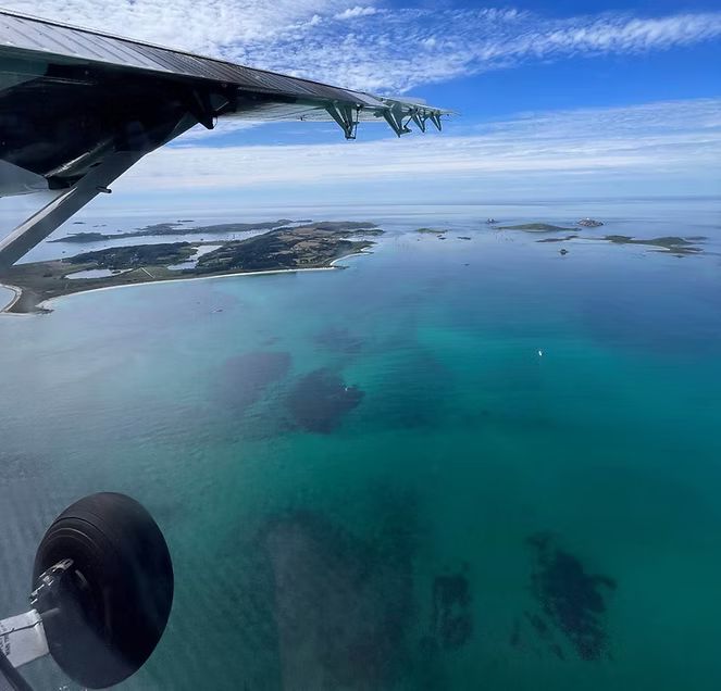 View from a plane of turquoise ocean, islands, and a partly cloudy sky.