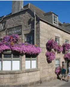 Atlantic pub with hanging purple flowers; two people outside on a sunny day.