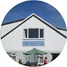White building with a blue sky background. A sign reads,