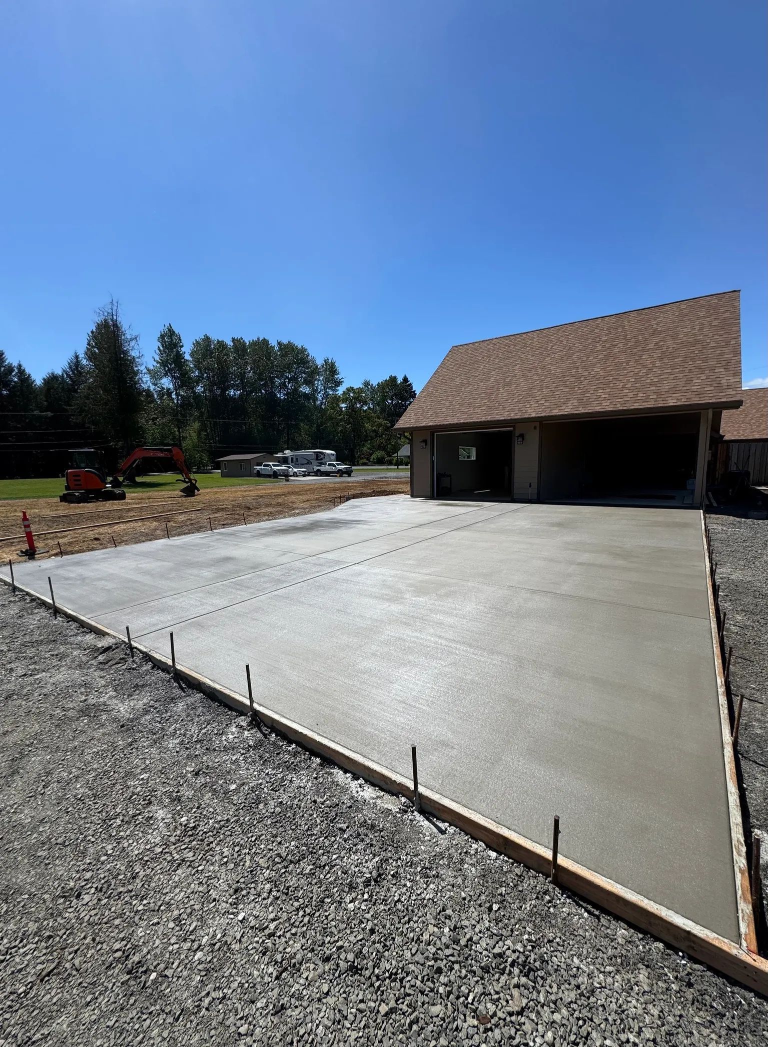A freshly poured concrete driveway leading to a garage under a clear blue sky.