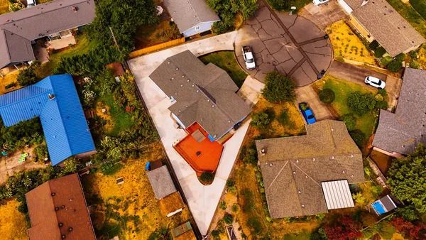 Aerial view of a residential neighborhood with houses, rooftops, driveways, and trees.