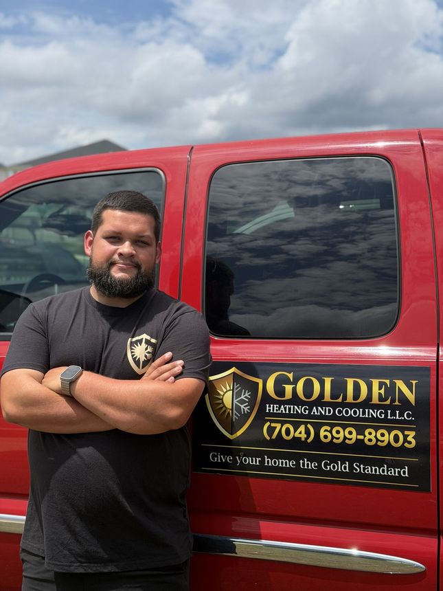 Man standing with arms crossed beside a red Golden Landscaping truck with logo and phone number.