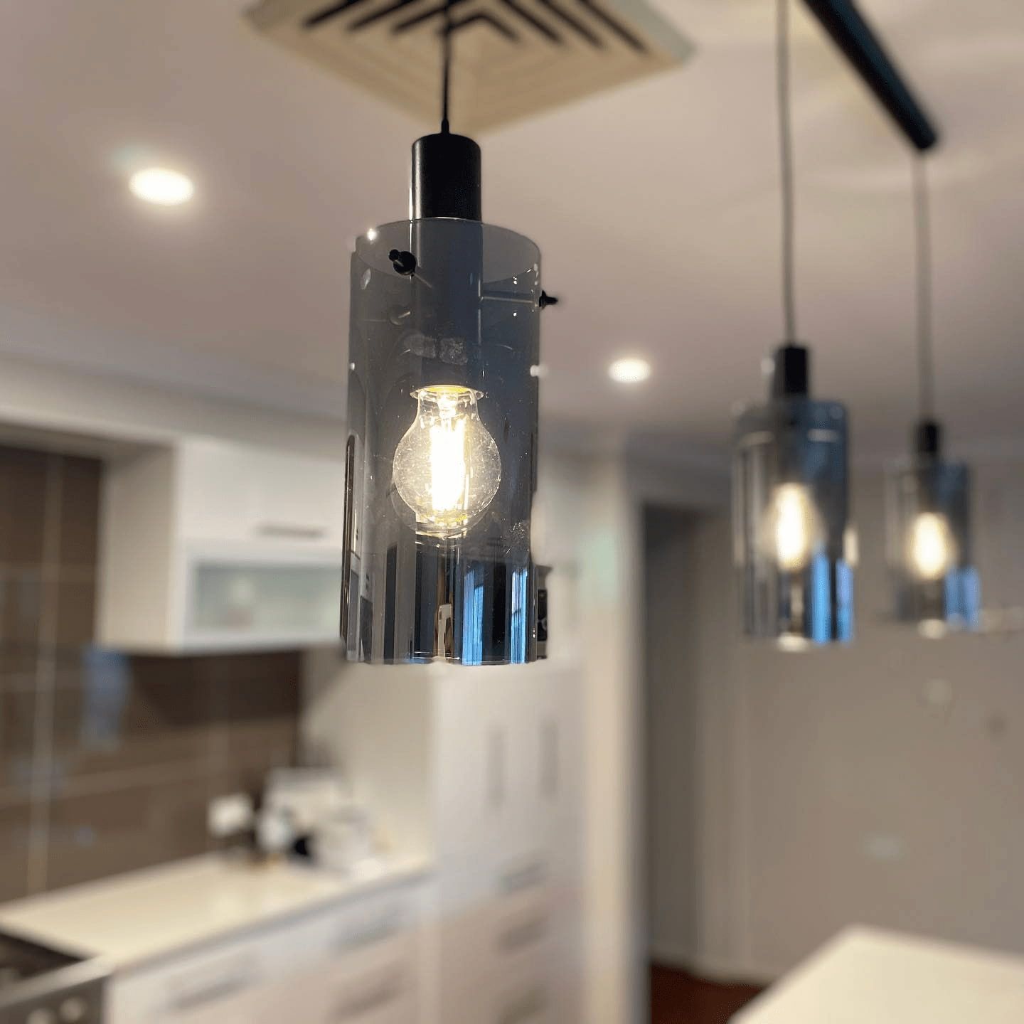 Three Hanging Gray Glass Pendant Lights With Edison Bulbs Over a Kitchen Counter — Hspark Electrical PTY LTD in Woonona, NSW