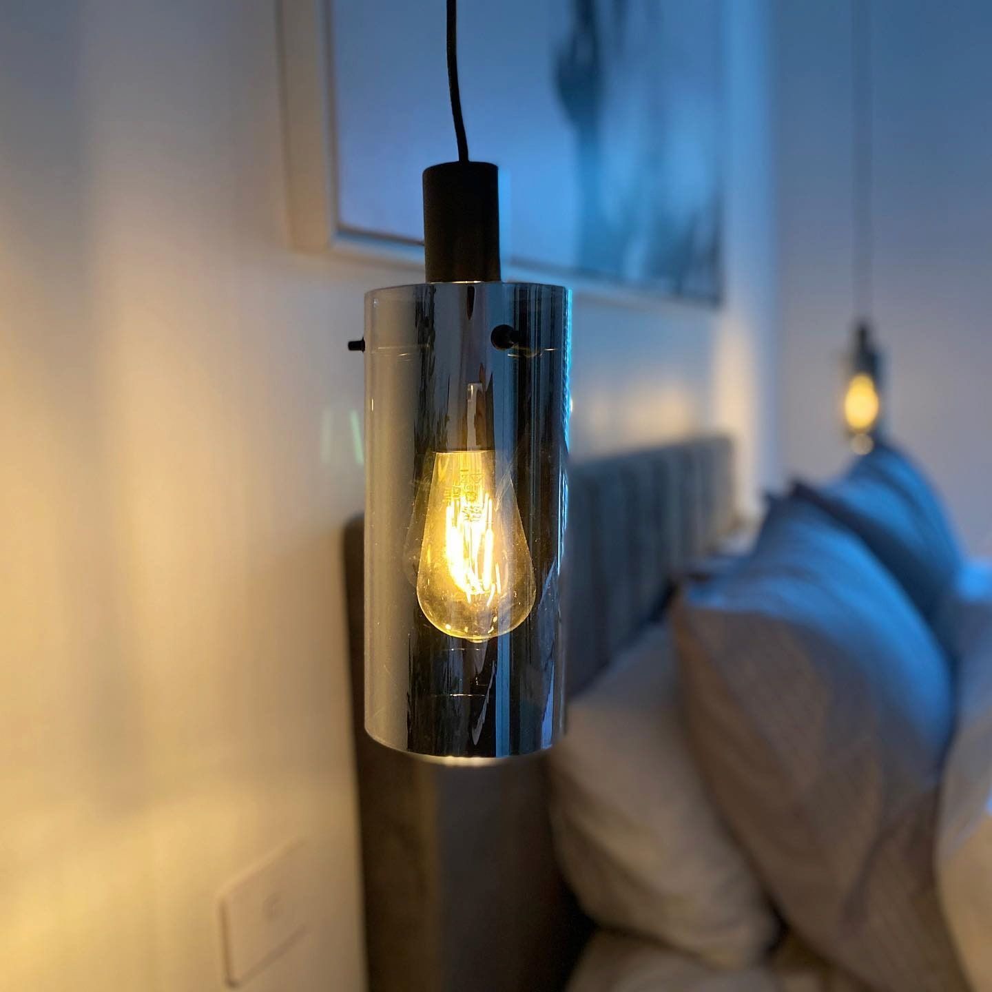 Chrome Pendant Light With a Lit Edison Bulb Hanging Over a Bed With Pillows — Hspark Electrical PTY LTD in Campbelltown, NSW