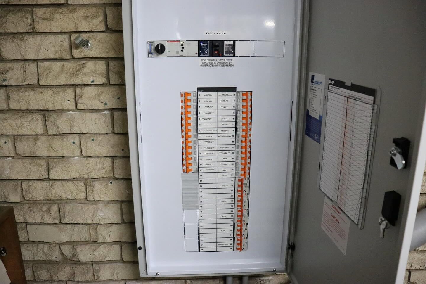 Electrical Panel With Rows of Circuit Breakers on a Brick Wall — Hspark Electrical PTY LTD in Wollongong, NSW