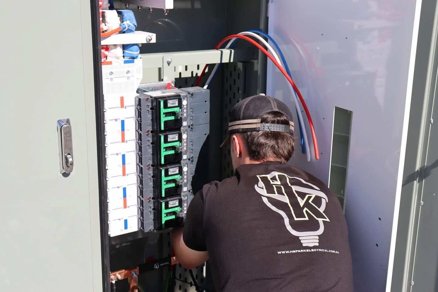 Electrician Working on Electrical Panel, Wearing a Black Shirt — Hspark Electrical PTY LTD in Appin, NSW