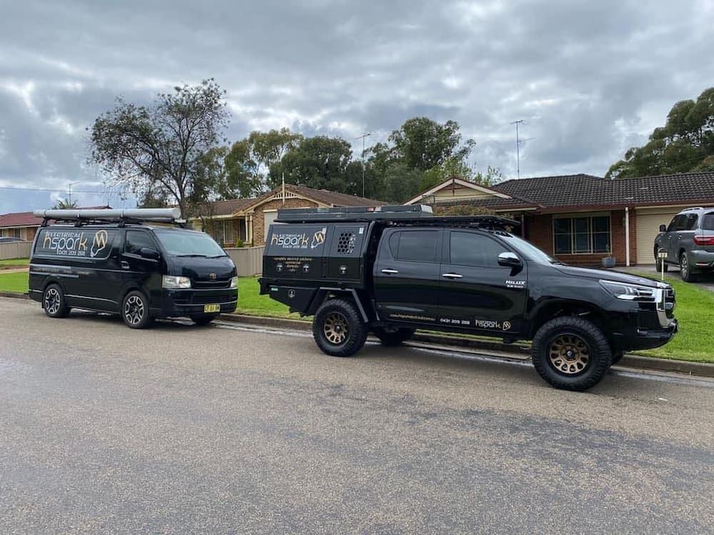 Black Toyota Hilux and Van Parked on a Residential Street — Hspark Electrical PTY LTD in Corrimal, NSW