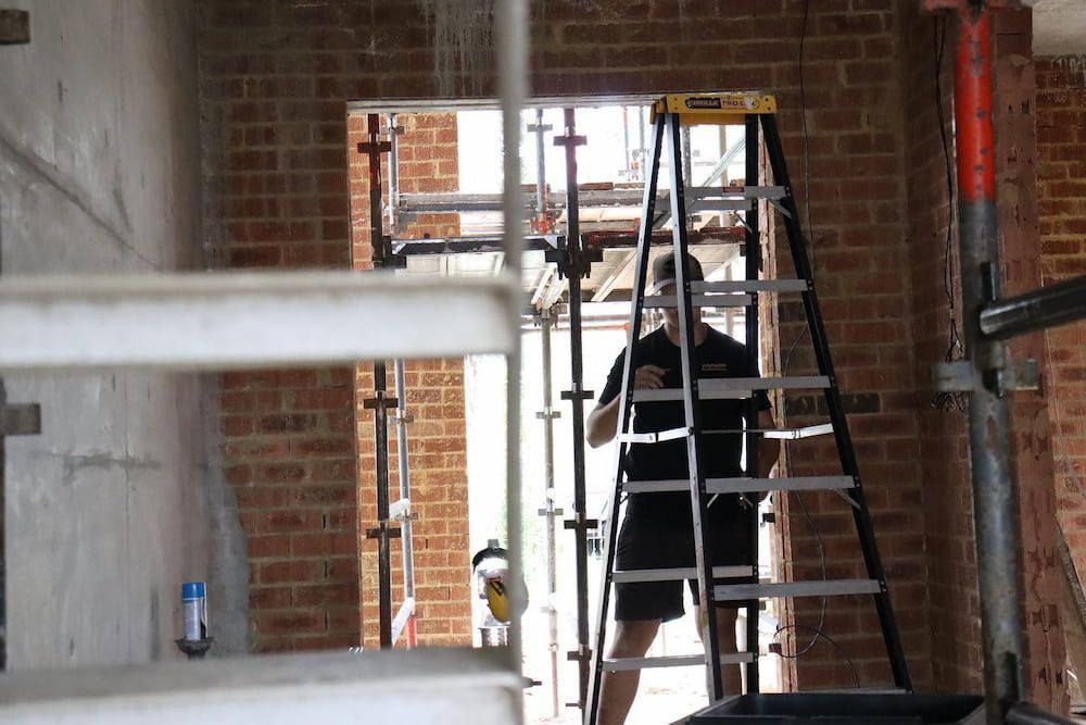 Man on Ladder in Construction Site Doorway — Hspark Electrical PTY LTD in Wilton, NSW