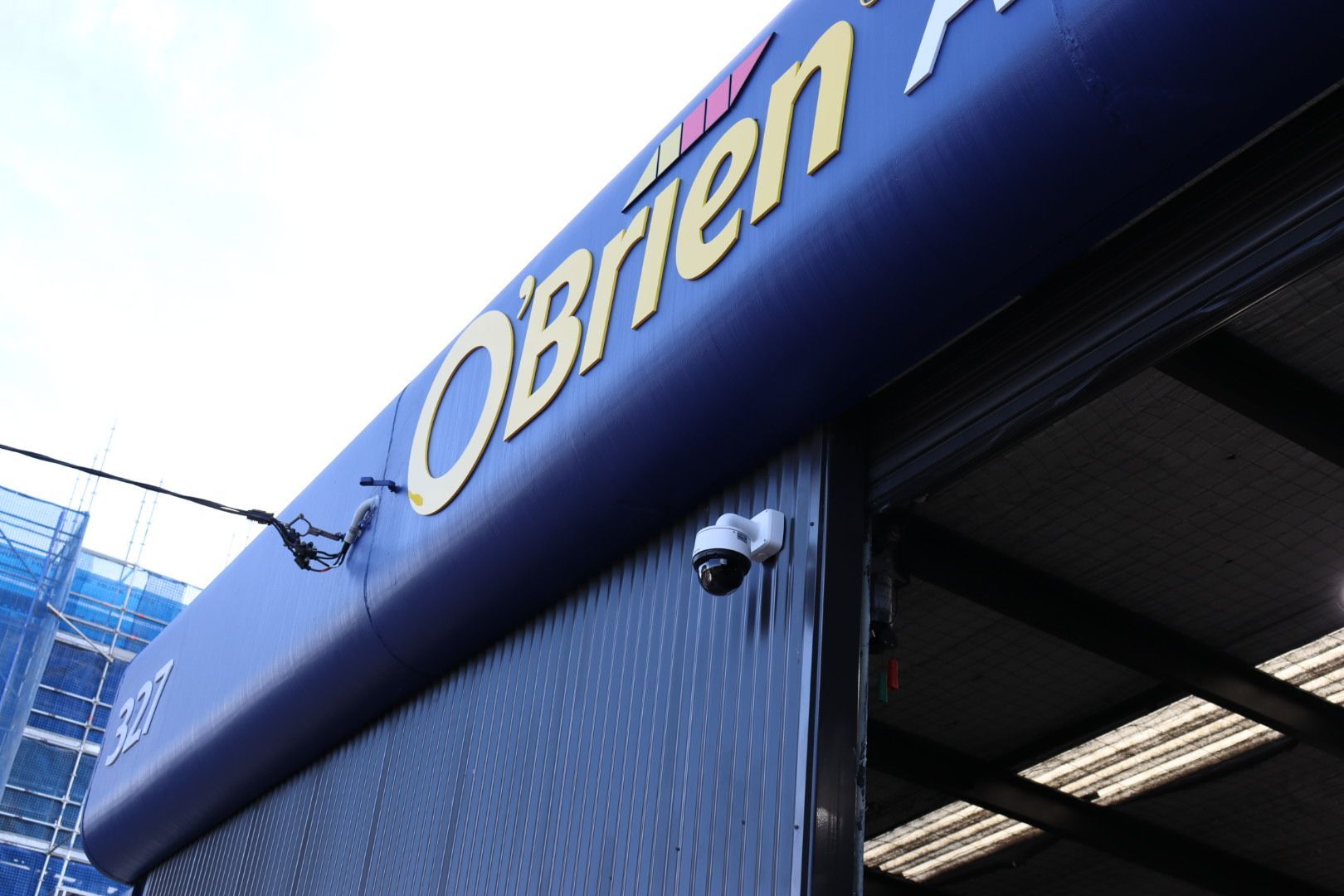 A white security dome camera mounted on the dark blue exterior wall under an 