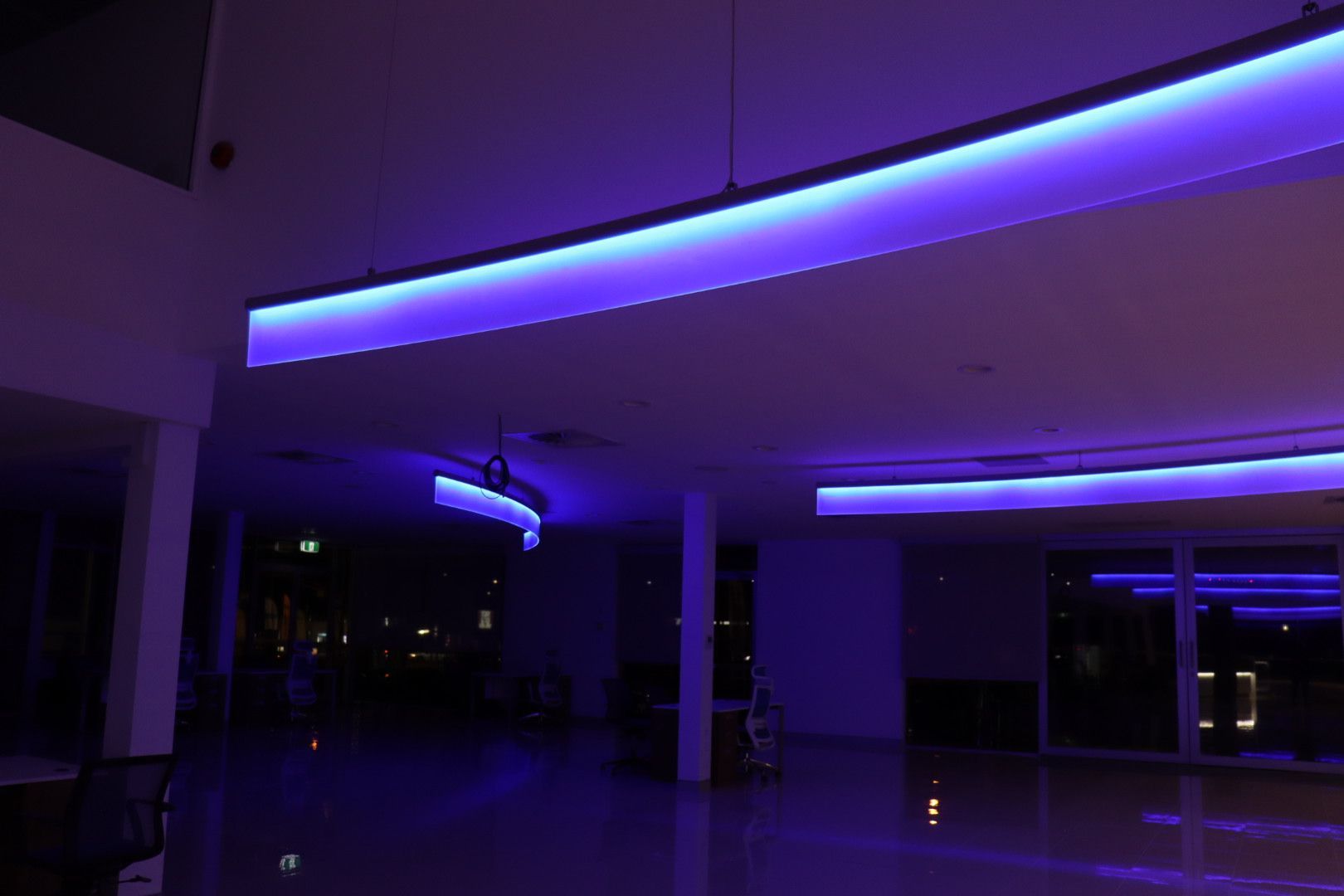A dark, modern interior space illuminated by curved, glowing purple strip lights recessed into the ceiling  — Hspark Electrical PTY LTD in Wollongong, NSW