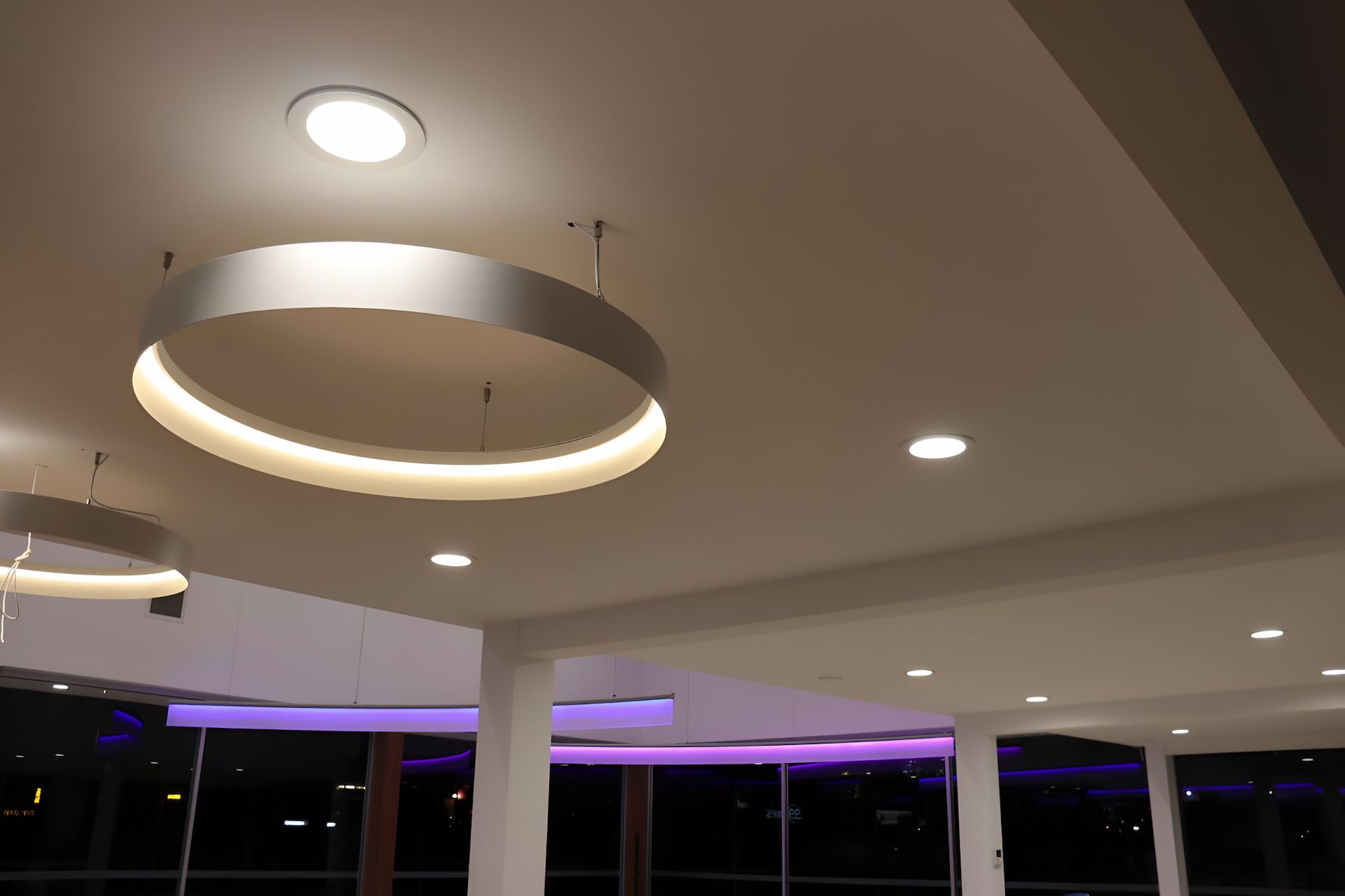 Interior view of a modern ceiling featuring circular pendant lights, recessed downlights, and ambient purple lighting — Hspark Electrical PTY LTD in Austinmer, NSW
