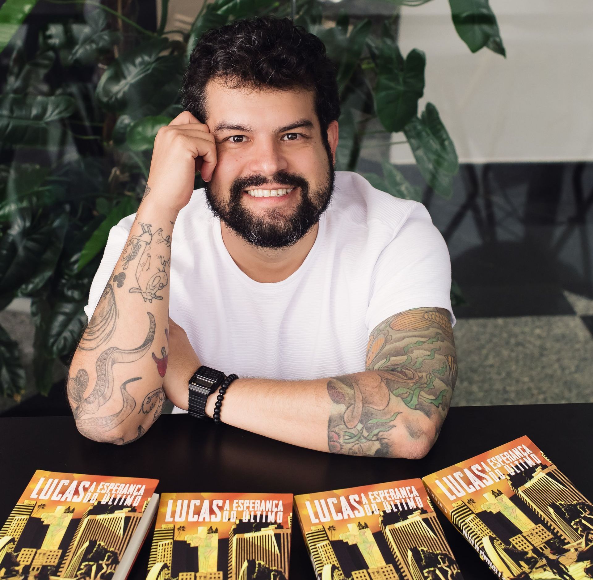 Um homem com tatuagens senta-se à mesa com lucas remando livros