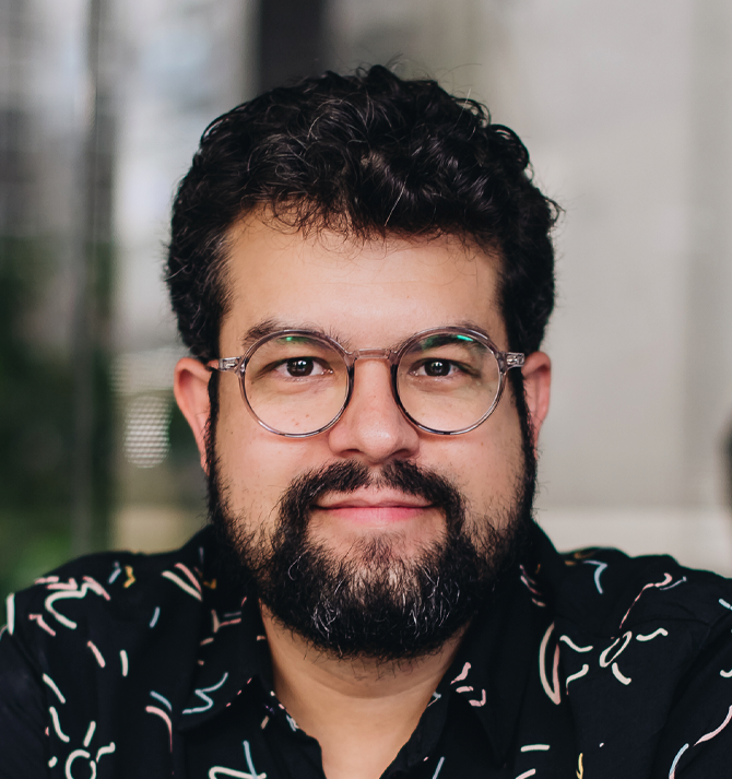 Um homem com barba usando óculos e uma camisa preta