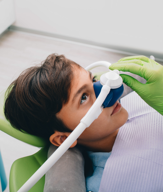 A young boy is laying in a dental chair with an oxygen mask on his face | Pediatric dentist near Tarrytown NY