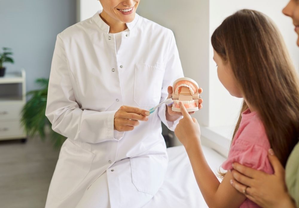Pediatric dentist near Tarrytown, NY talking to their young patient A young boy is sitting in a dental chair and smiling at the dentist.