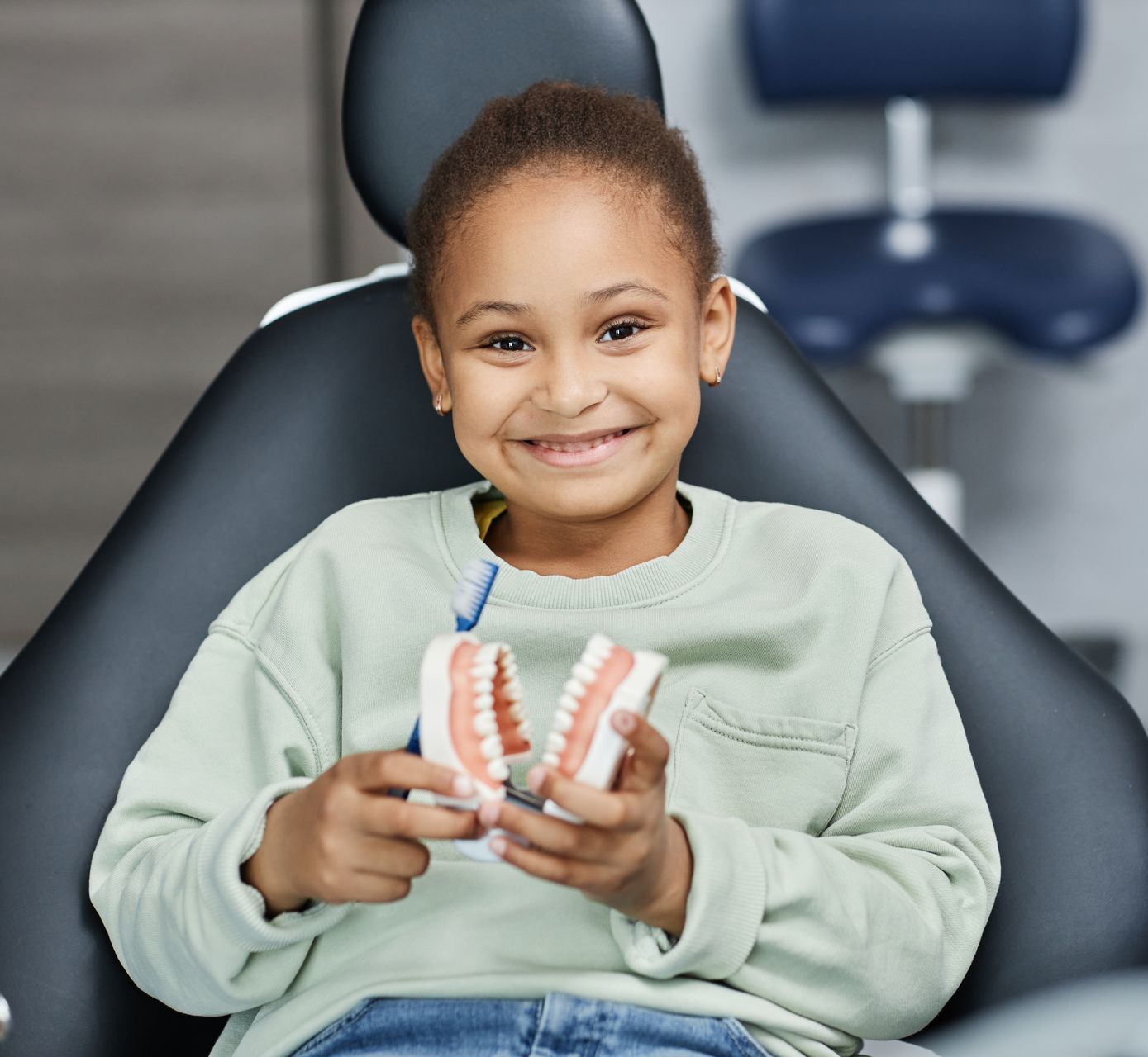 A young child sitting in a dental chair and smiling. Restorative dental care for kids in Tarrytown, NY