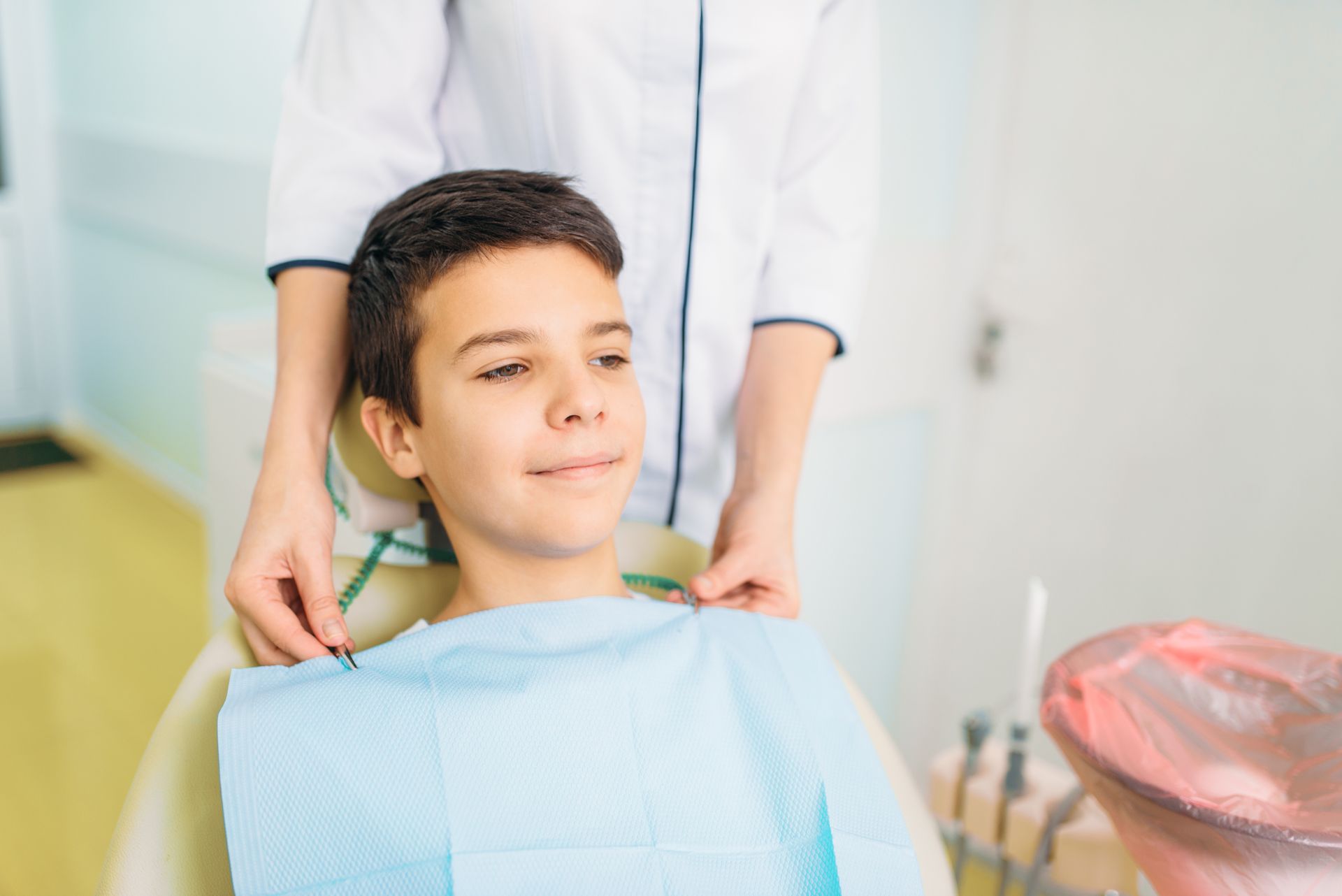 A young boy is sitting in a dental chair being examined by a dentist.