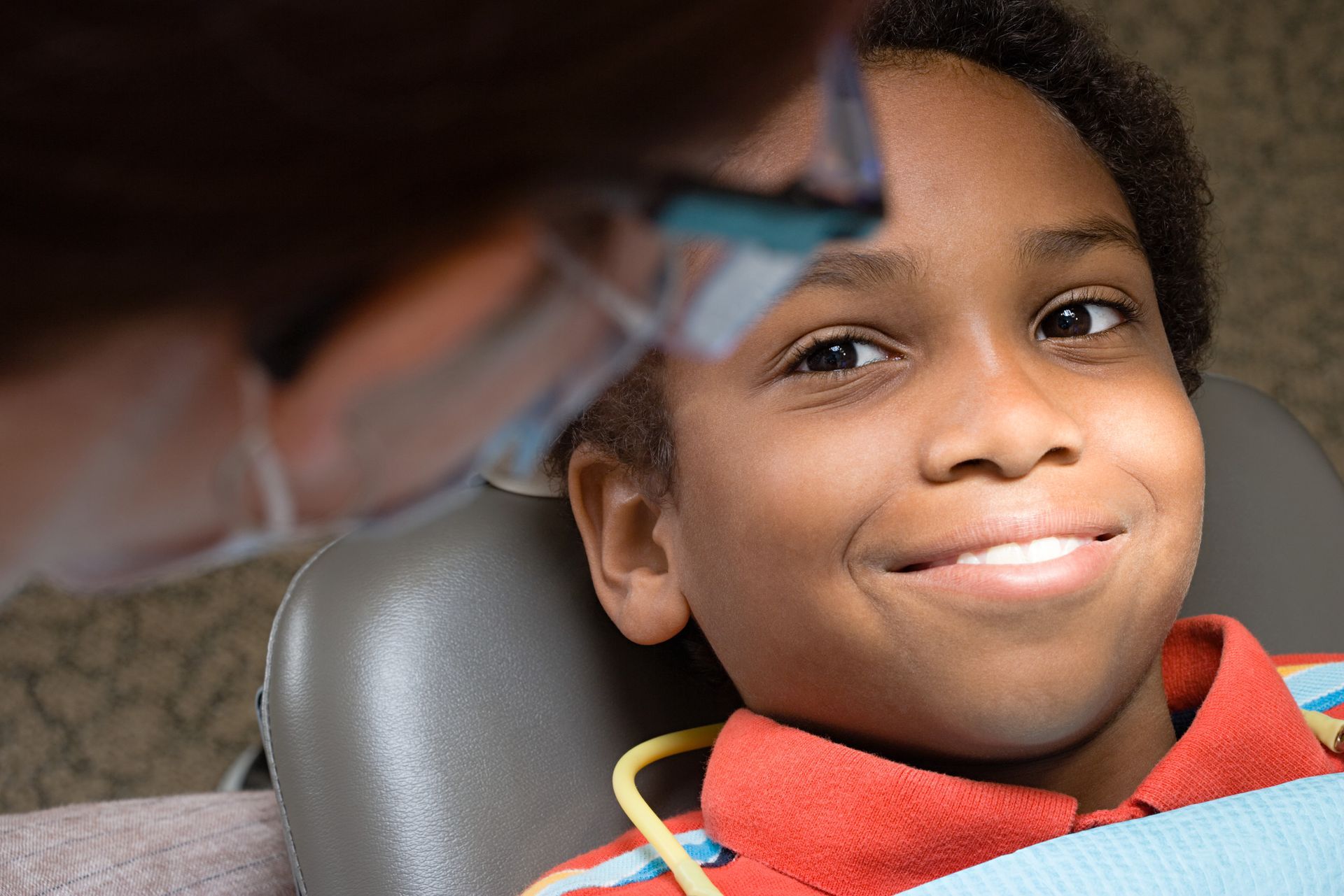 A young boy from Tarrytown NY is smiling while sitting in a dental chair.