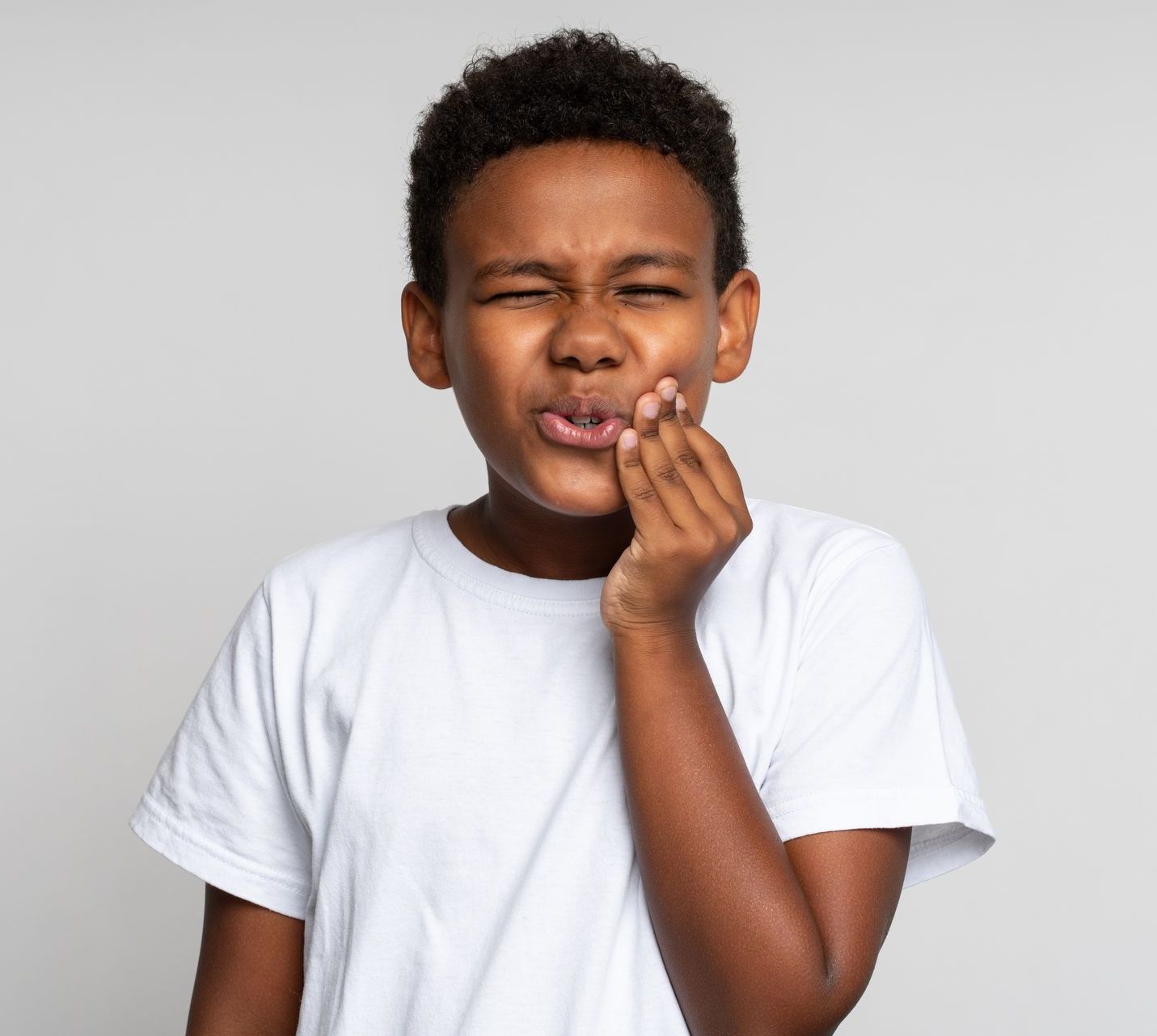 A young boy is holding his mouth in pain because of a toothache, emergency pediatric dental care in Tarrytown, NY