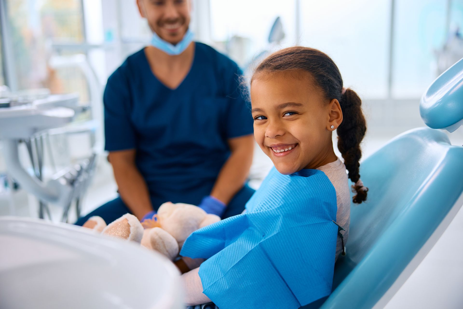 A little girl is sitting in a dental chair and smiling, emergency pediatric dental care in Tarrytown NY