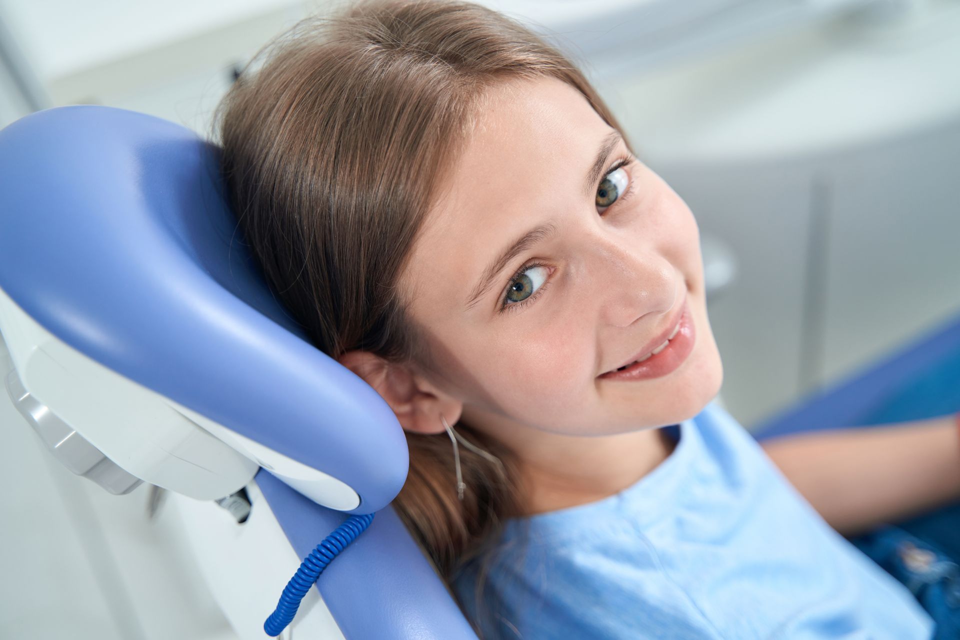 A young girl is sitting in a dental chair and smiling, non-invasive dental treatments in Tarrytown, NY