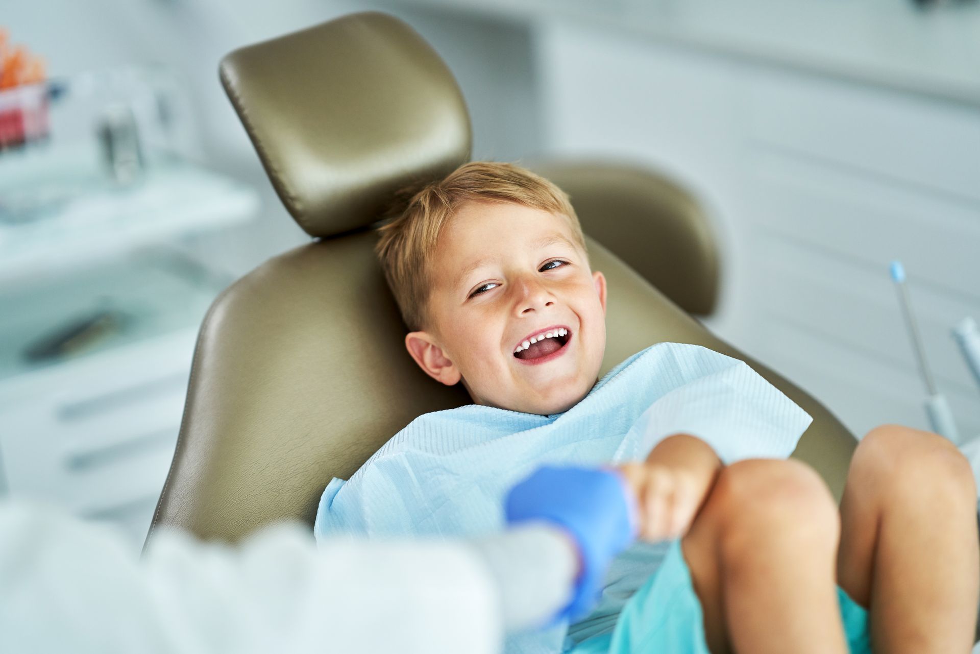 A young boy is sitting in a dental chair and smiling.