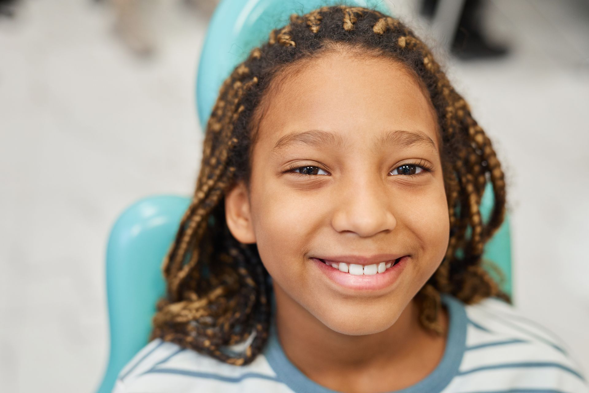 A young girl is smiling while sitting in a dental chair.
