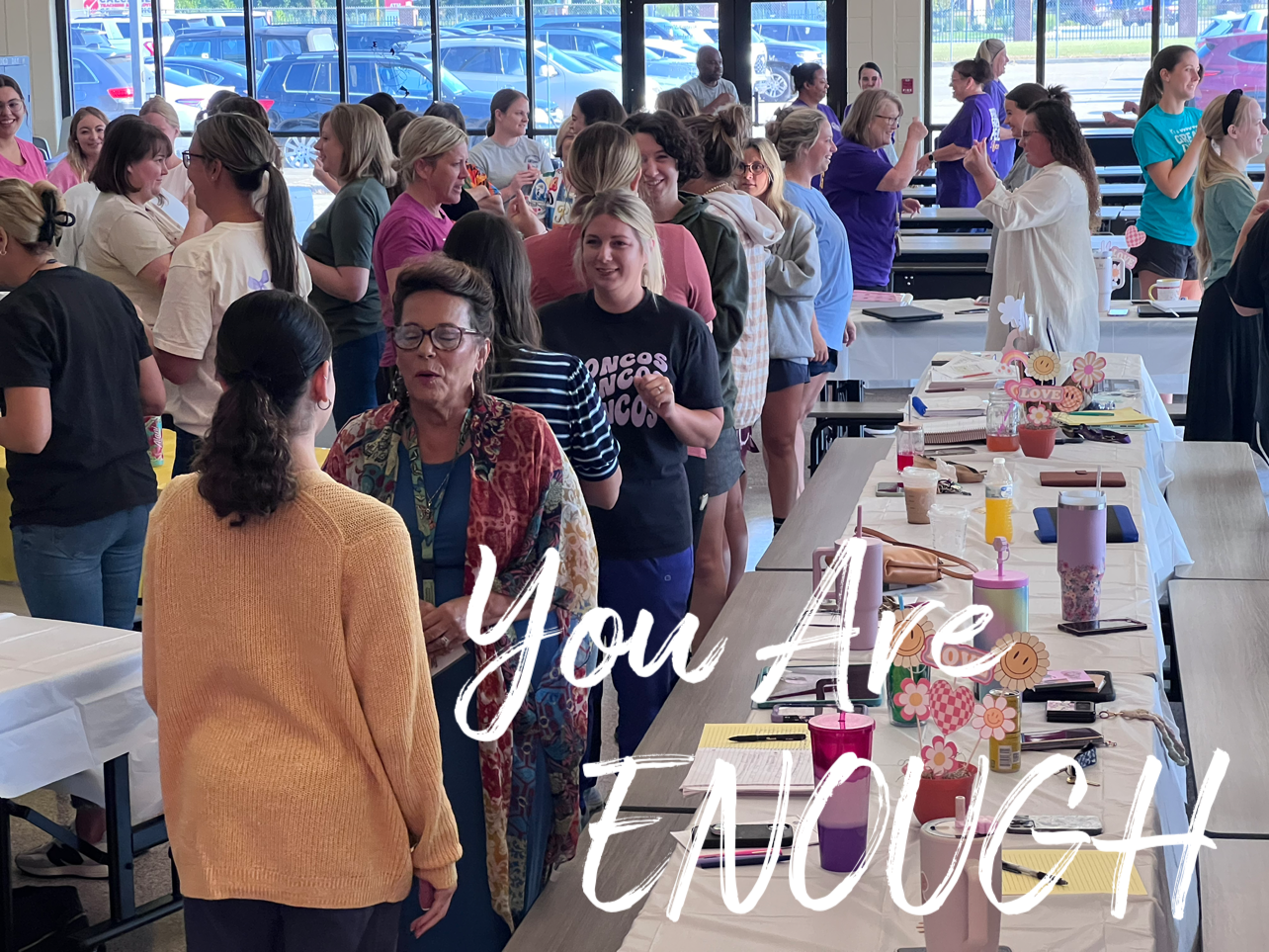 A group of people are standing around a table with the words `` you are enough '' written on it.