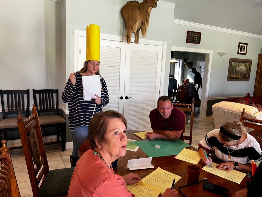 A group of people are sitting around a table in a living room.