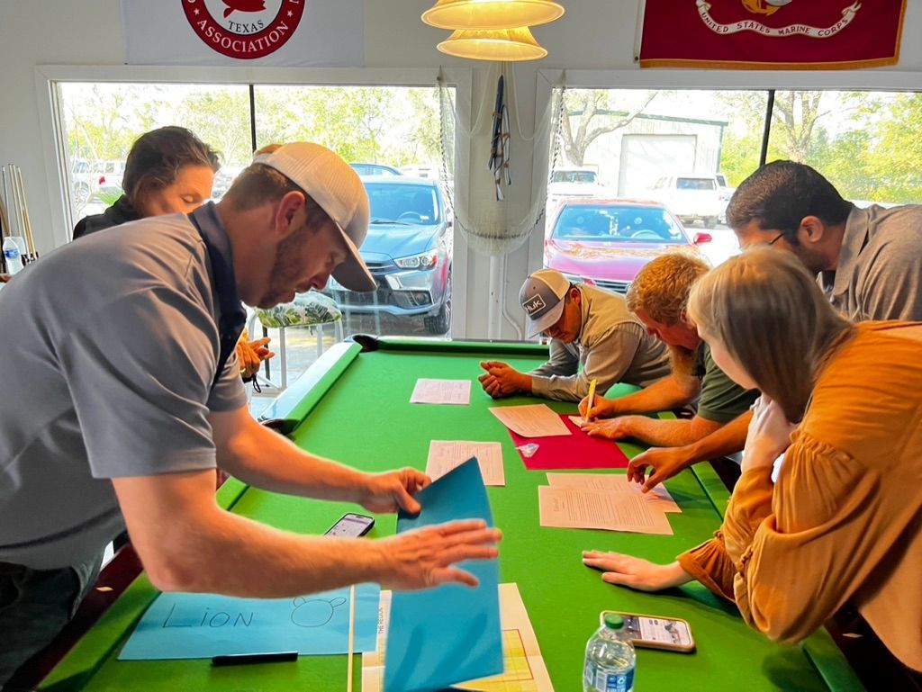 A group of people are sitting around a pool table.