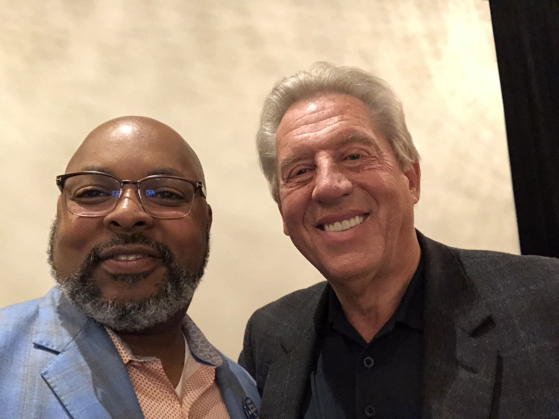 Two men are posing for a picture together and smiling for the camera.