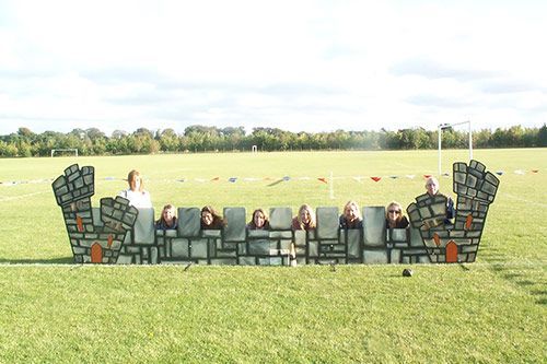 A group of people are standing behind a castle made out of bricks.