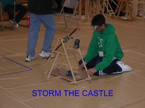 A boy in a green hoodie is kneeling on the floor with a castle in the background
