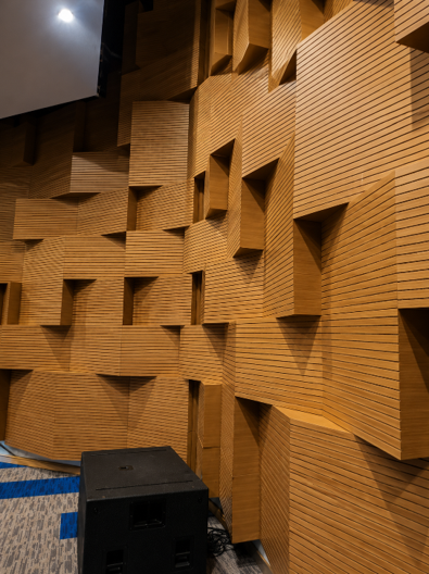 Wood-paneled acoustic wall with geometric protrusions in a theater or auditorium interior