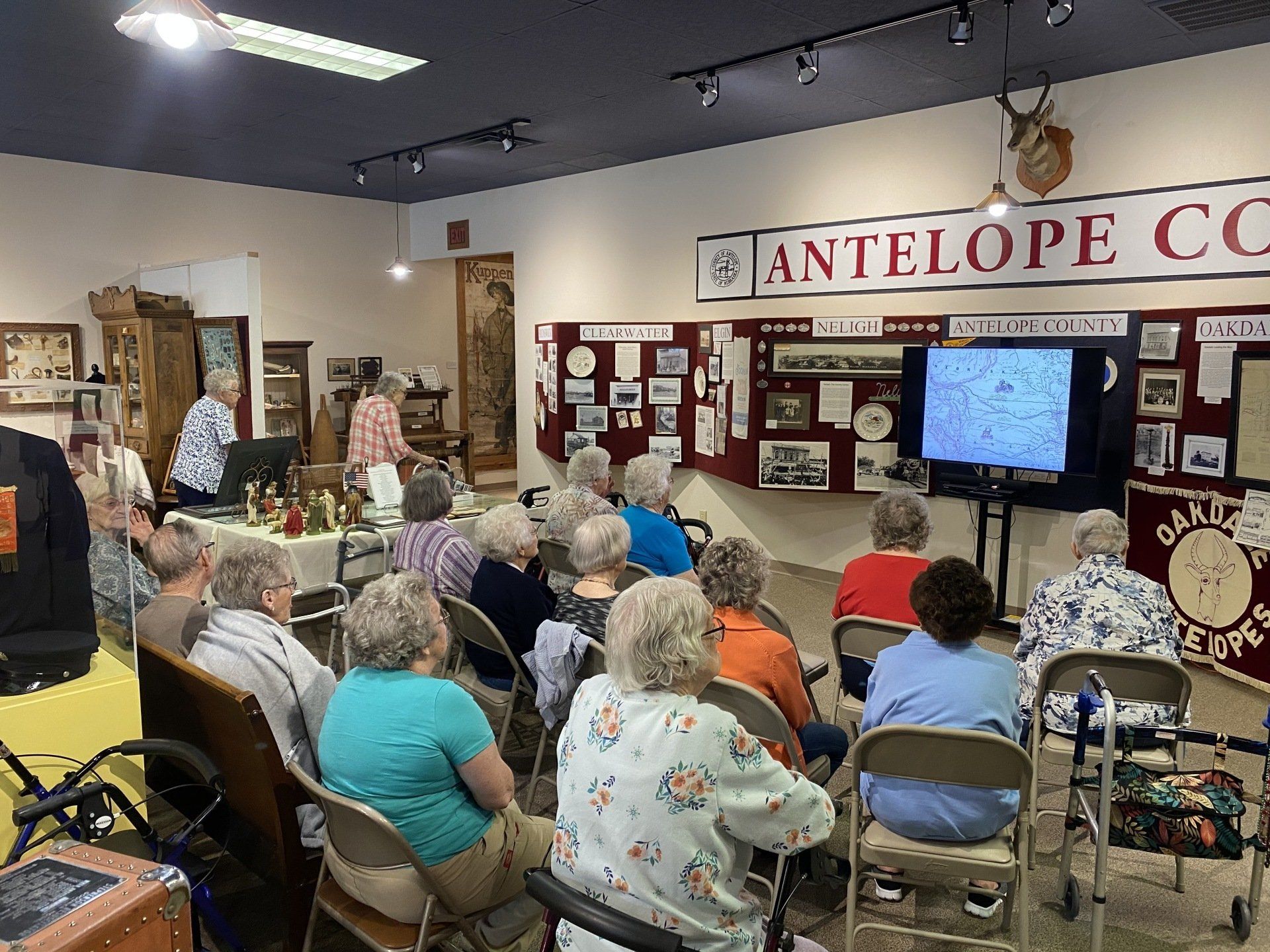 A group of people watch a presentation at the Antelope County Historical Society.