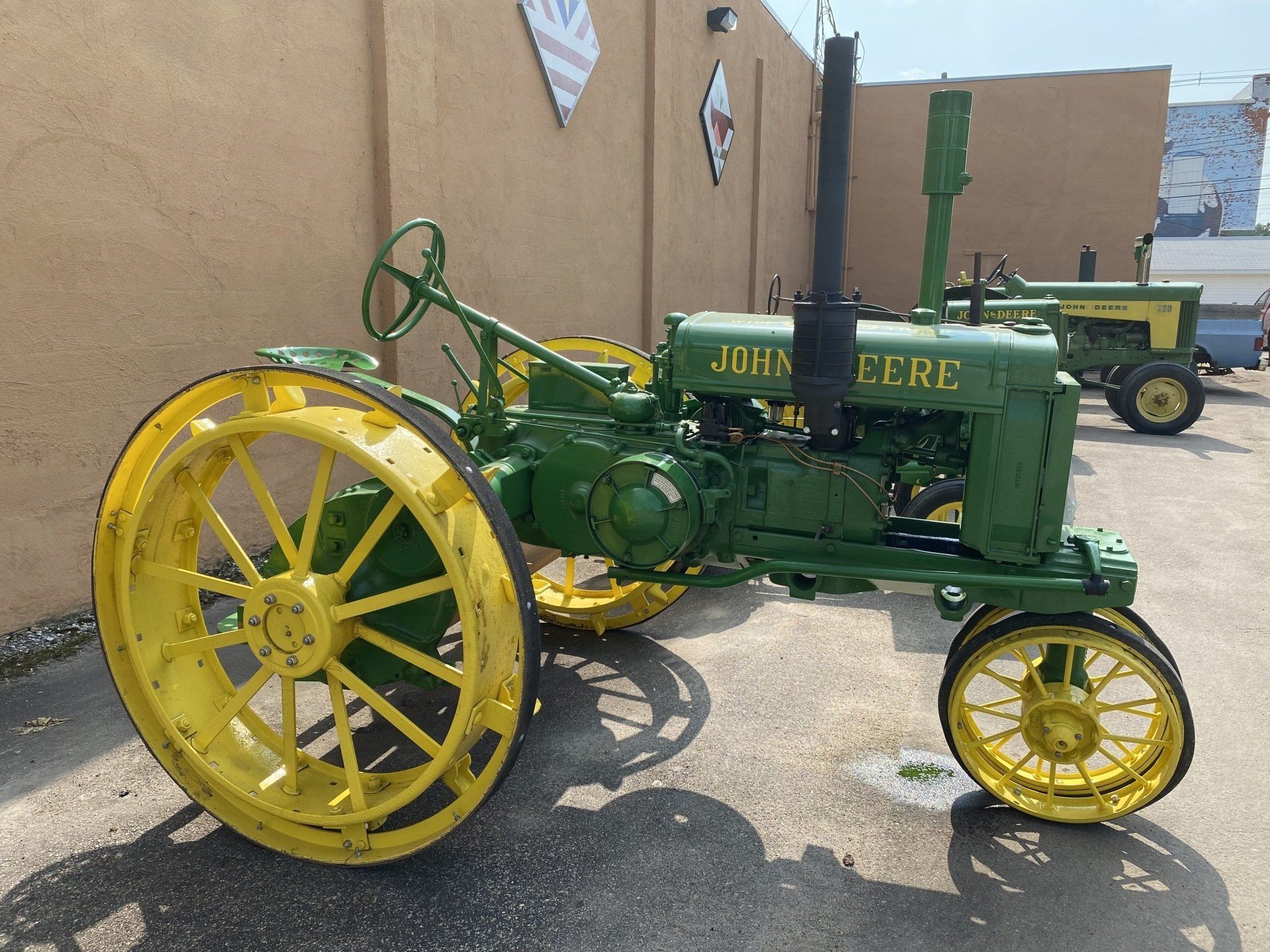 Green and yellow John Deere tractor parked outside; another tractor in background.