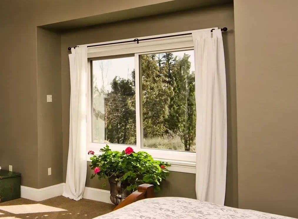 A bedroom with a large window and white curtains