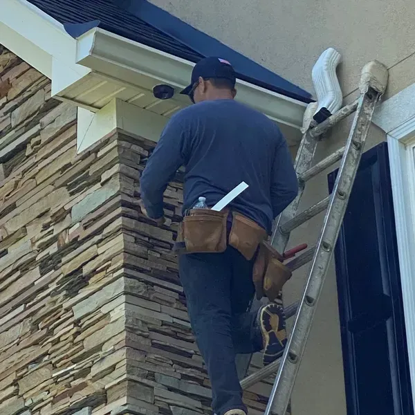 A man is standing on a ladder on the side of a building