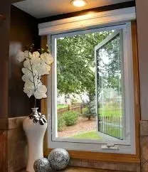 A kitchen window with a vase of flowers and balls in front of it.