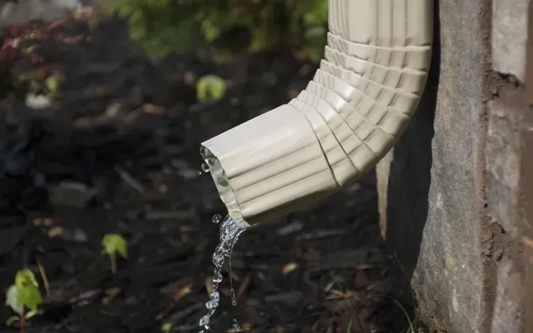 A close up of a drainpipe with water coming out of it.
