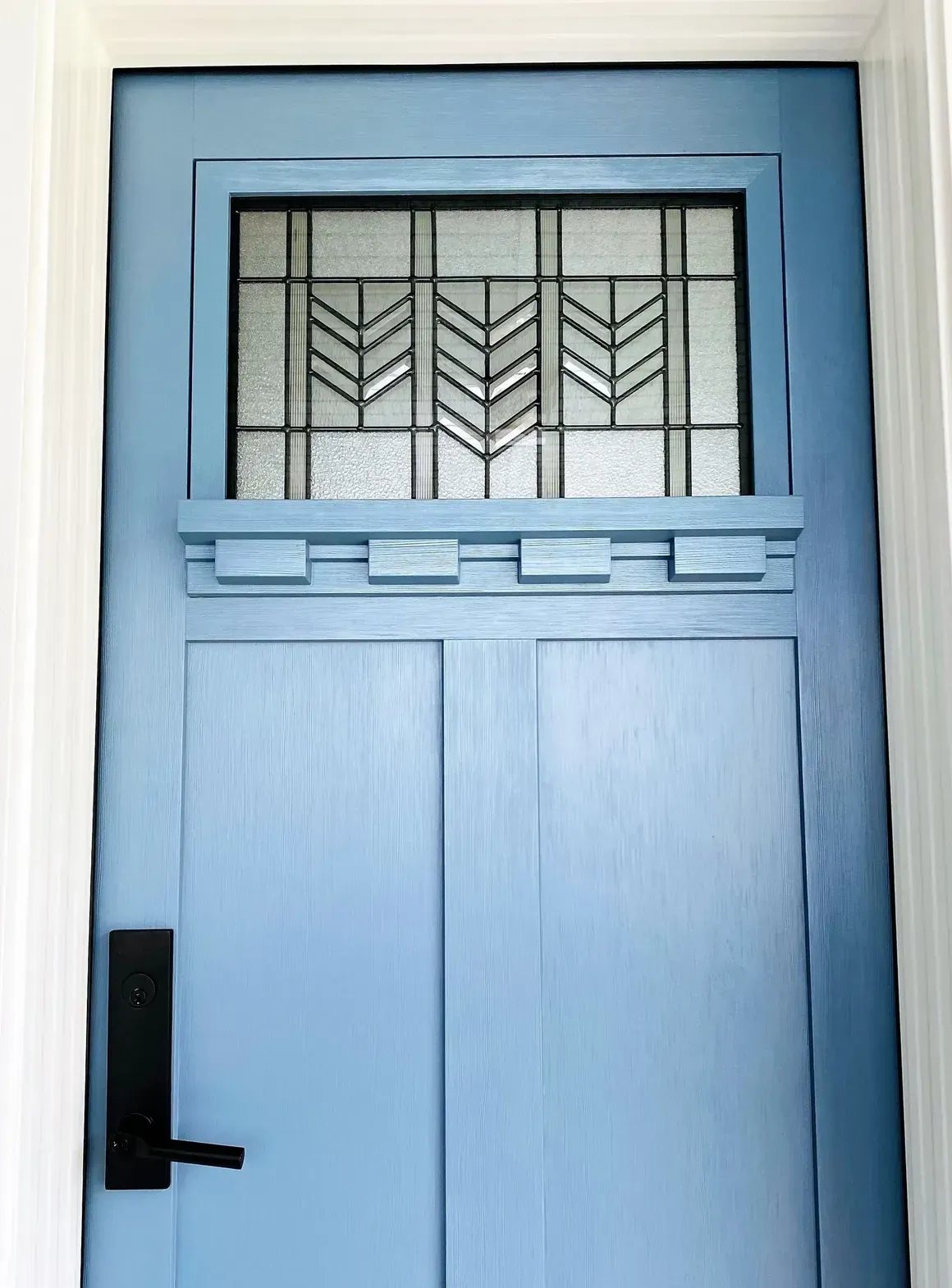 A blue door with a stained glass window and a black handle.