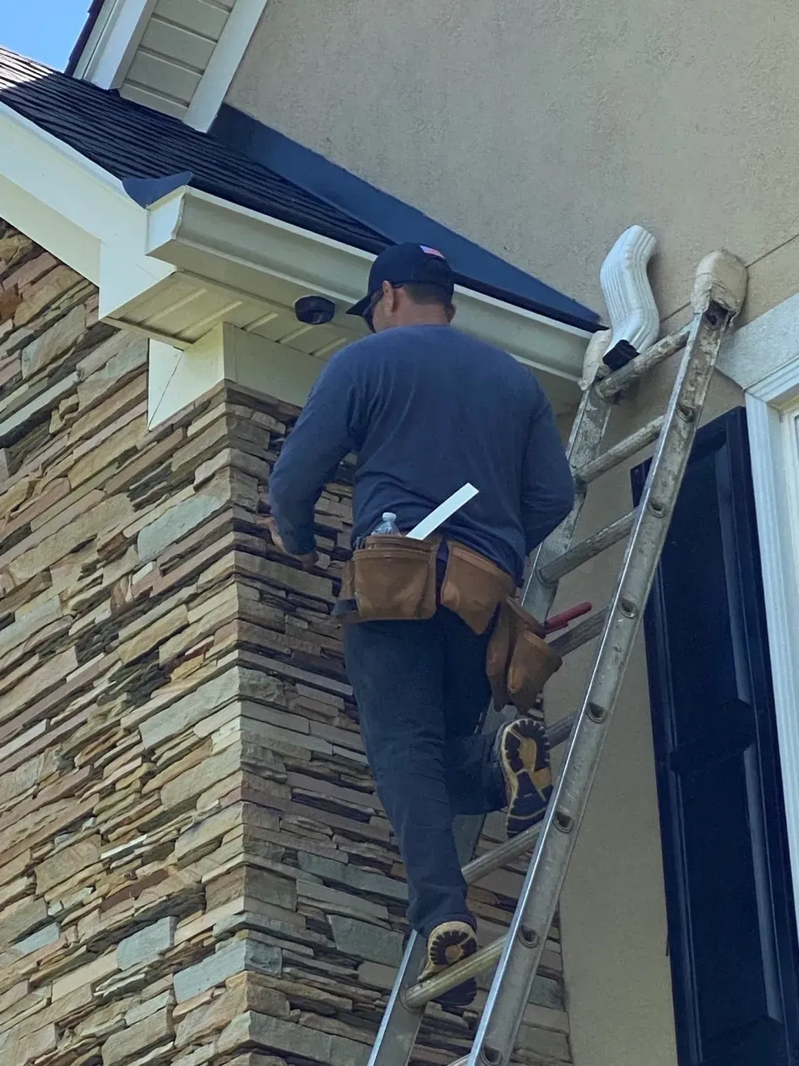 A man is standing on a ladder on the side of a building.