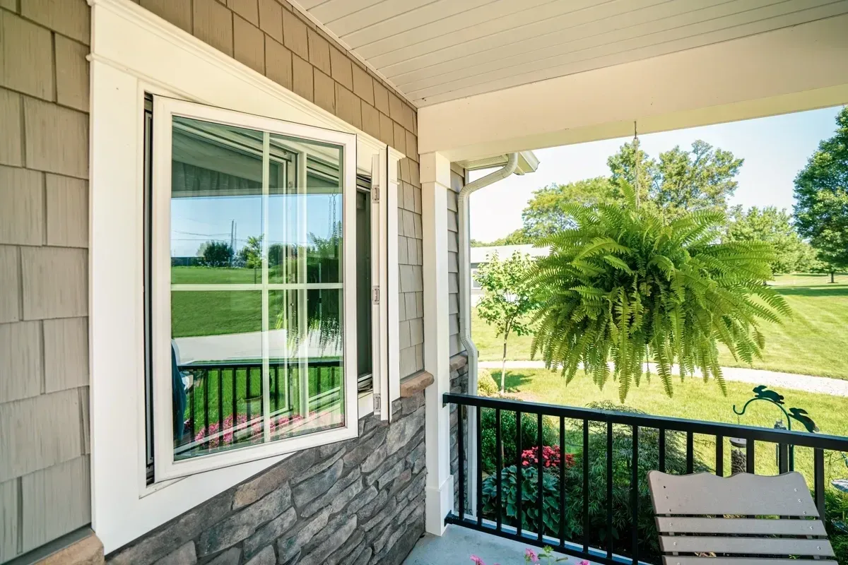 A porch with a white window and a black railing.