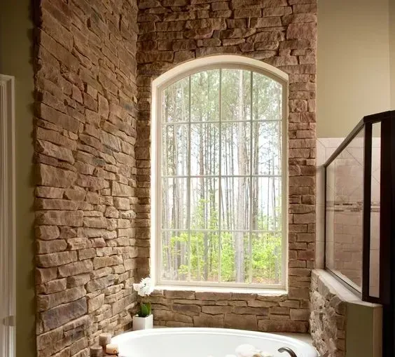 A bathroom with a tub and a window with trees in the background