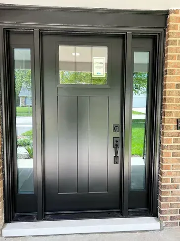 A black front door is sitting on top of a brick building.